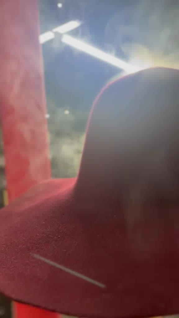 Steam pressing a colored felt hat into its final form